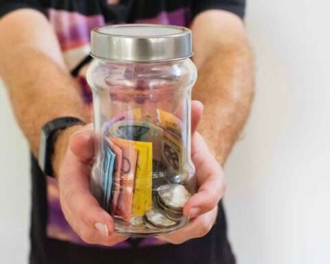 person holding clear glass jar filled with money