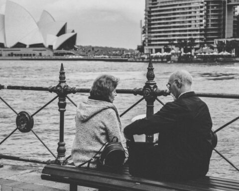 greyscale photo of man and woman sitting on bench