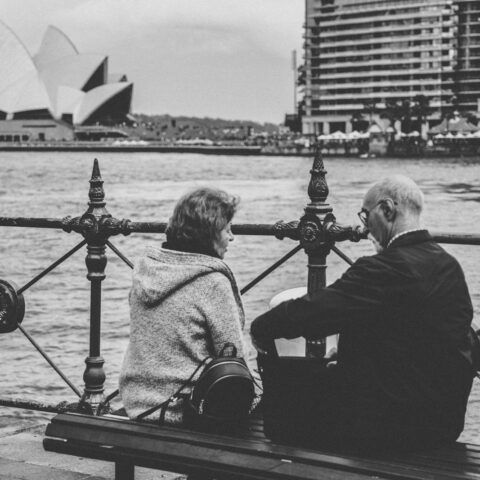 greyscale photo of man and woman sitting on bench